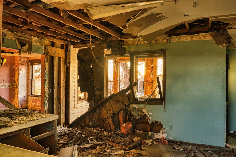 A view of a severely damaged room in an abandoned home, showcasing destruction and rubble.